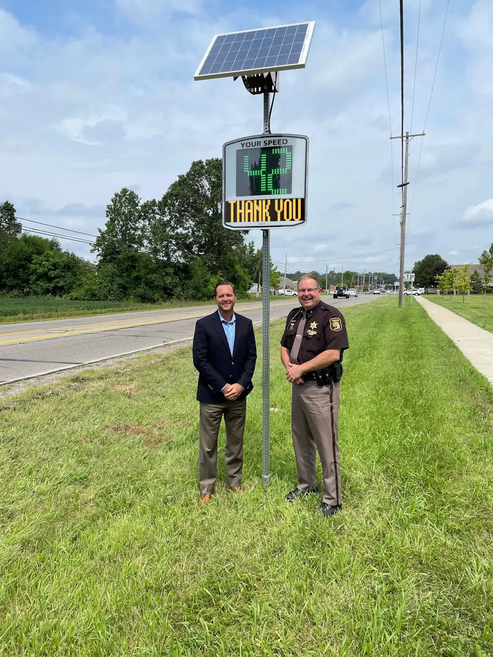 A major and a sheriff in front a EVOLIS radar speed sign installed in a city in the US